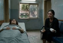 A dimly lit, narrow medical clinic room rendered in muted, desaturated tones of grey and pale blue. In the foreground, a young woman lies on a worn clinic bed, her eyes fixed on the ceiling, her bandaged hands resting motionless on a thin blanket. Beside her, an older woman sits hunched on a shabby sofa, her face pale and hollow-eyed, her own bandaged hands resting in her lap, tears streaming silently down her weathered cheeks. Between them on the floor, scattered shards of broken glass catch the weak fluorescent light. Through a small grimy window in the background, barely visible outside, a large overflowing garbage dumpster sits beneath a jasmine tree, its white blossoms falling softly. The atmosphere is heavy with grief, disconnection, and unspoken generational pain. Cinematic, literary realism style with dramatic chiaroscuro lighting, evoking isolation and emotional devastation.